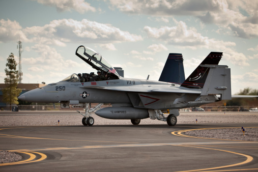 Scottsdale, Arizona USA - November 5, 2011: F-18 fighter jet on taxi way with crewman waving American flag.