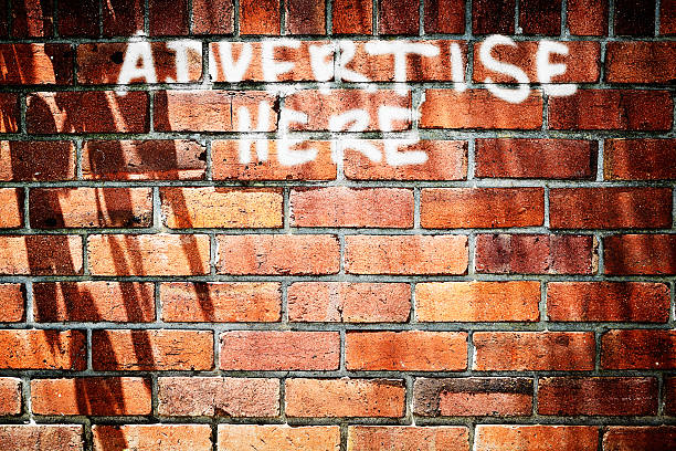 istock Cheeky chalked graffiti on brick wall reads Advertise Here 459403385