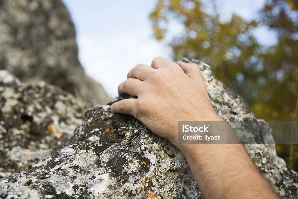 Climber holding rock Rock climber’s hand grasping handhold on natural cliff. Activity Stock Photo