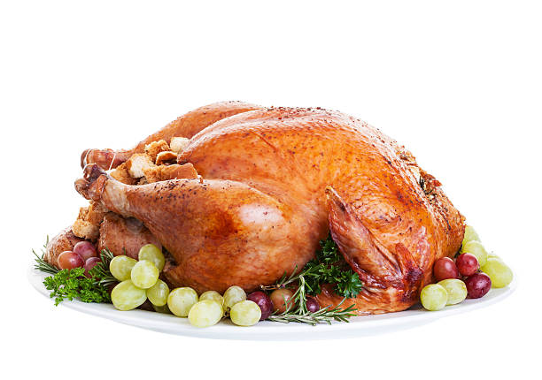 Whole cooked turkey on plate with red and green grapes A large a stuffed turkey on a platter garnished with grapes. turkey thanksgiving dinner cooked stock pictures, royalty-free photos & images