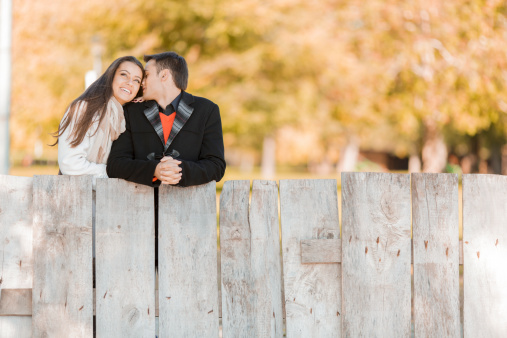 Young couple by the wooden fence