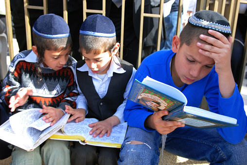 Jerusalem, Israel- March 4, 2007: Three Jewish children reading Holy Hebrew books in a quiet side of the famous Western Wall of Jerusalem.