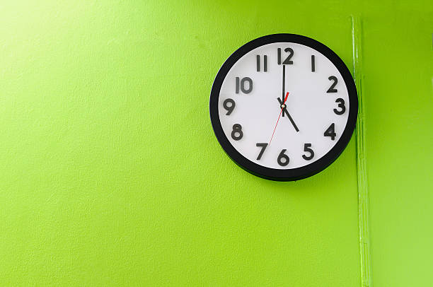 Clock signaling 5 o'clock hung on a lemon-green wall Clock showing 5 o'clock on a green wall  five minutes timer stock pictures, royalty-free photos & images