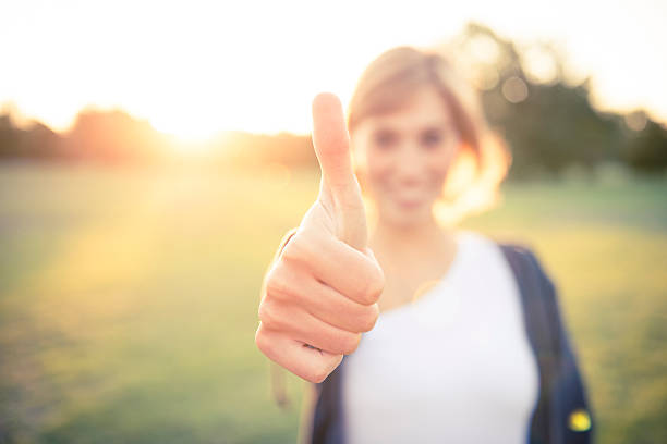A young woman with her thumb up outside stock photo