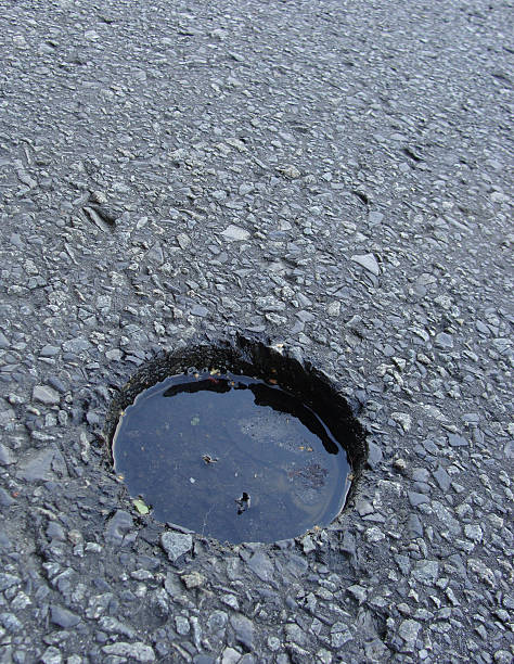 istock circular hole in asphalt road filled with water 459435277