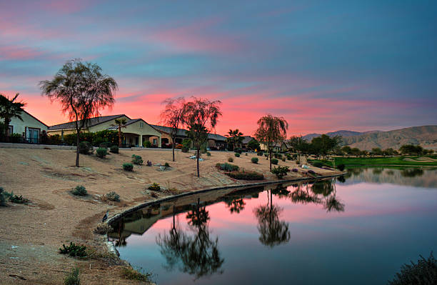 golf course Large houses and curvy landscape in a rich suburb. Homes in a golfing community. Sunset reflected in lake palm desert pool stock pictures, royalty-free photos & images