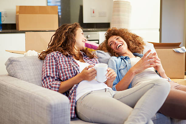 istock Two Women On Sofa With Hot Drink In New Home 459442135