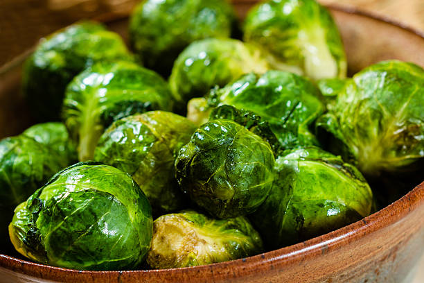 Freshly cooked Brusells Sprout in a bowl. Freshly cooked, glistening Brussels Sprout in a pottery bowl. cruciferous vegetables stock pictures, royalty-free photos & images