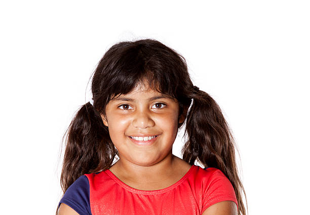 Happy, smiling, Hispanic girl with pigtails and wearing a gymnastics leotard.