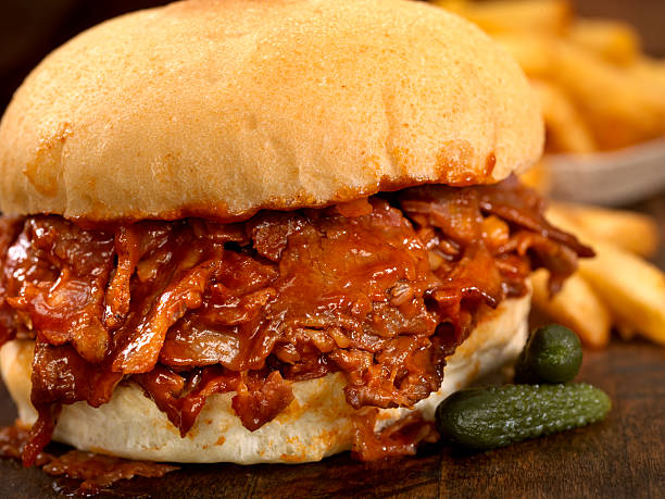 BBQ Beef Brisket Sandwich BBQ Beef Brisket Sandwich, Slow Cooked Beef Brisket thinly Sliced and Smothered in BBQ Sauce and a side of Fries- Photographed on Hasselblad H3D2-39mb Camera barbecue beef stock pictures, royalty-free photos & images