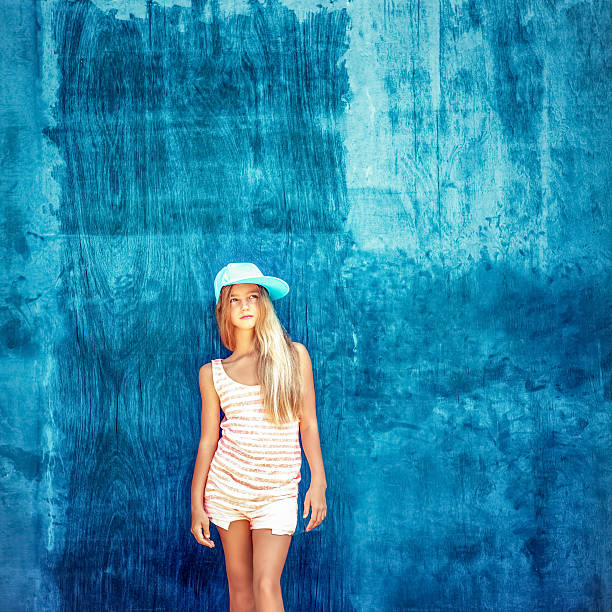 teenage girl in the cap with a blue wall stock photo