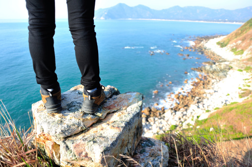 hiking feet stand at the rock on seaside mountain