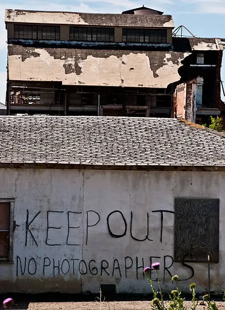 An abandoned sugar beet mill and graffiti saying "Keep Out - No Photographers" outside Loveland Colorado.
