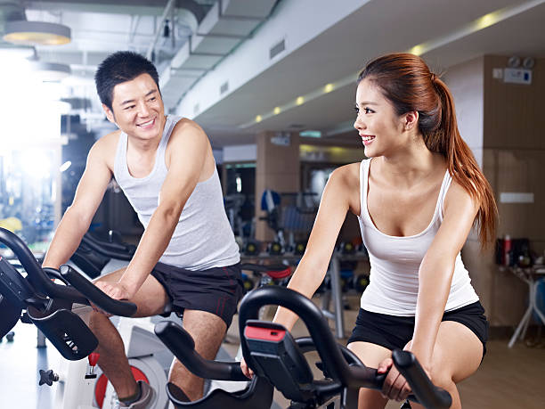 young man and woman talking while exercising on bicycle in fitness center. click for more: