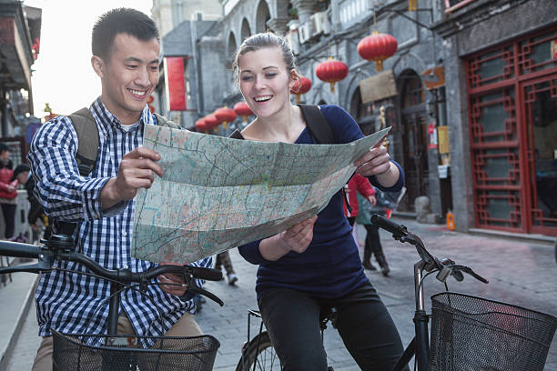 Young man and woman on bicycles, looking at map. stock photo