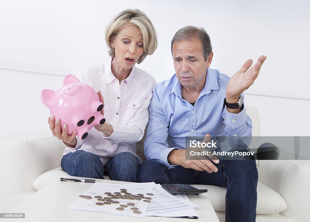 Shocked Couple Holding Piggybank Portrait Of Shocked Couple Holding Piggybank At Home Adult Stock Photo