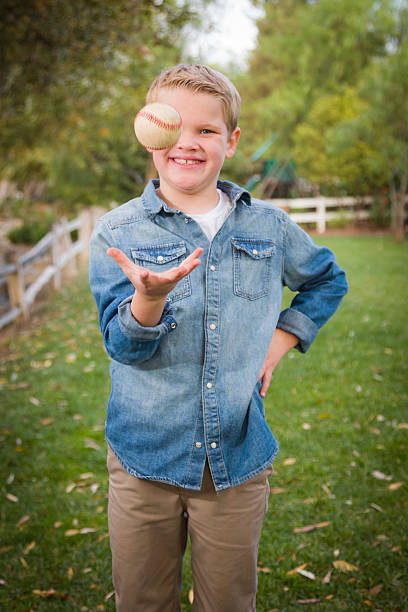 istock Handsome Young Boy Tossing Up Baseball in the Park 459524945