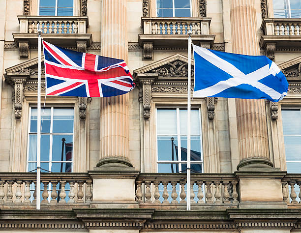 Union Flag and Scottish Saltire in Edinburgh A Union Flag and a Scottish Saltire flag flying in front of an Edinburgh office building exterior. scottish flag stock pictures, royalty-free photos & images