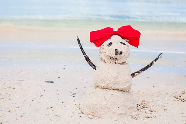 istock Little sandy snowman with bow on white Caribbean beach 459572035