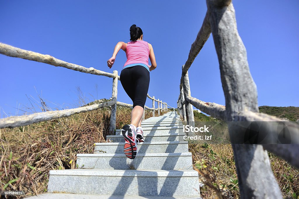 woman running up on mountain stairs back of healthy woman running up on mountain stairs Active Lifestyle Stock Photo