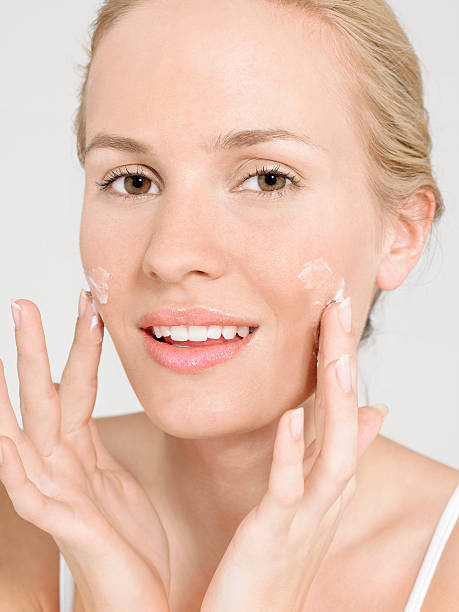 istock Young Woman Applying Facial Cream 459594613