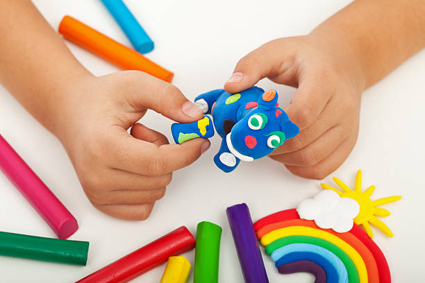 Plasticine modeling clay in children class. kids together play dough and  mold from plasticine in kindergarten or preschool. Group of four people.  Teaching modeling. Stock Photo