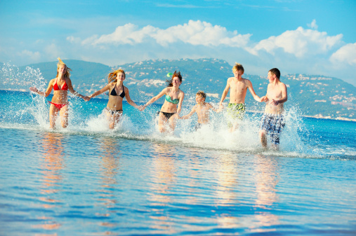 Group of  young friends running through the shallow water. Location: Cote d'Azur, France