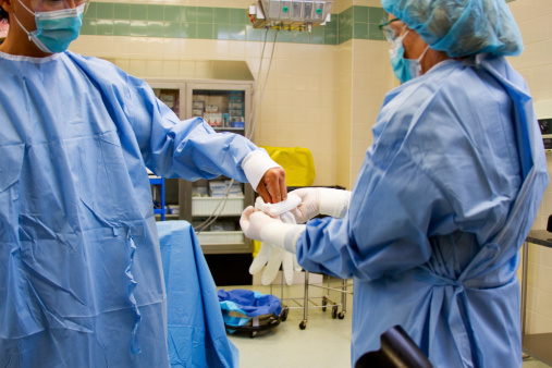 Doctor donning gloves for surgery in operating room