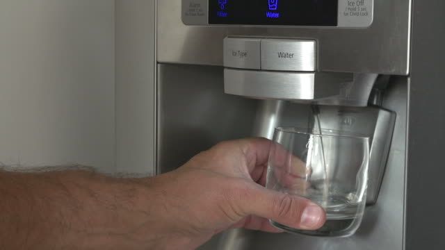 Close Up Of Man Getting Glass Of Chilled Water From Fridge