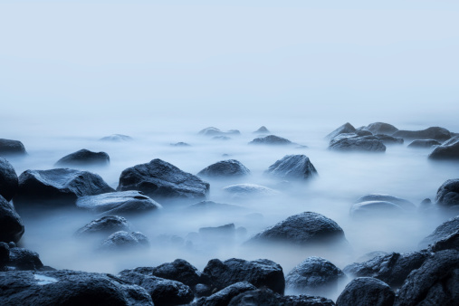 Long exposure of water over rocks on a foggy day.