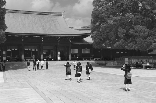 Tokyo, Japan - October 9, 2013: Visitors - including a group of schoolgirls dressed in school uniforms - at the Meiji Shrine (dedicated to the deified spirits of Emperor Meiji and his wife) on a sunny day in fall.