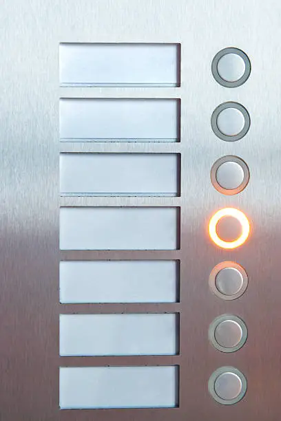 Close-up of an illuminated selection buttons with blank tags on a stainless steel button panel, these buttons are used to key in your selection.  Blank labels are ready to insert your individual text.