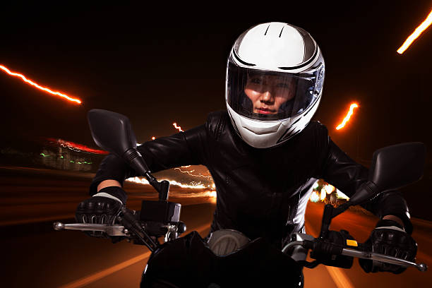 Young woman riding a motorcycle through the streets of Beijing, light trails