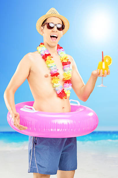 istock Smiling man in swimming shorts holding a cocktail on beach 459861645