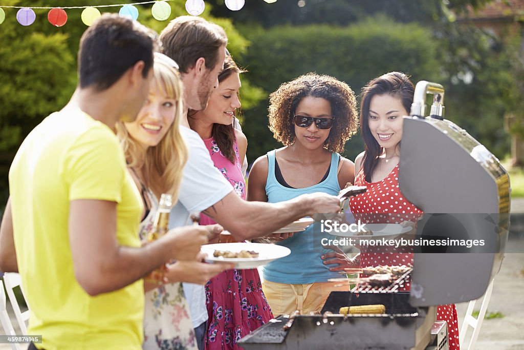 Group Of Friends Having Outdoor Barbeque At Home Group Of Friends Having Outdoor Barbeque At Home In Garden Grilled Stock Photo