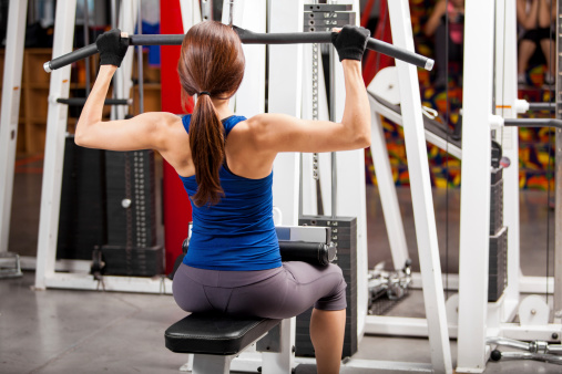 Athletic young woman lifting some weights and building muscle in a gym