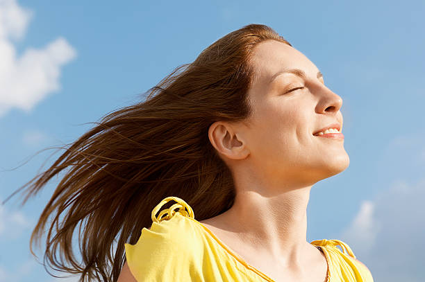 istock Woman With Eyes Closed Enjoying Sunlight Against Sky 459877239