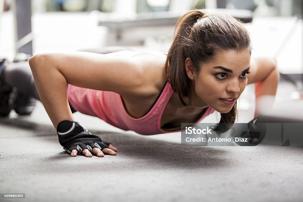 Doing some push ups at the gym Beautiful Latin woman doing push ups in the gym before lifting some weights Exercising Stock Photo