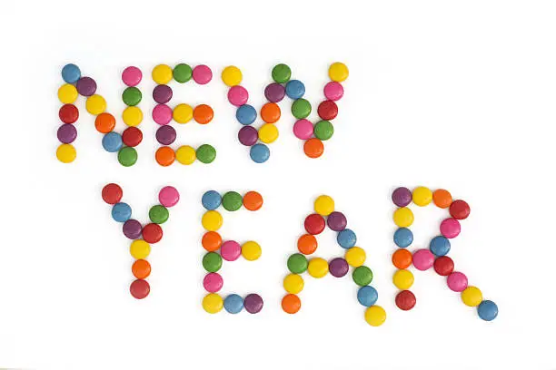 The title NEW YEAR written of the colored smarties. Festive theme.