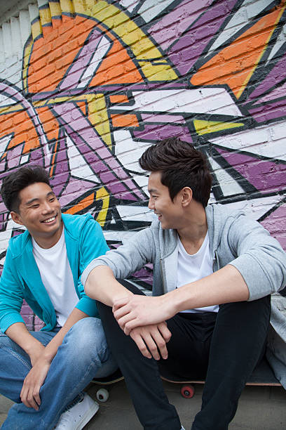 istock Two young men hanging out in front of graffiti wall 459887687
