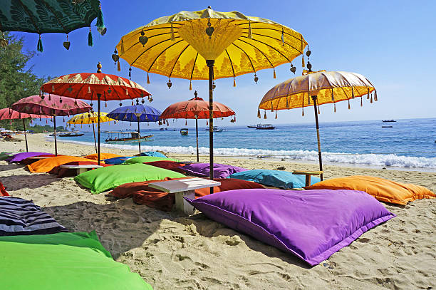 Pristine beach bathed by the Bali Sea This image shows some colourful beach umbrellas and sand pillows in a pristine tropical beach bathed by the Bali sea. chaise longue photos stock pictures, royalty-free photos & images