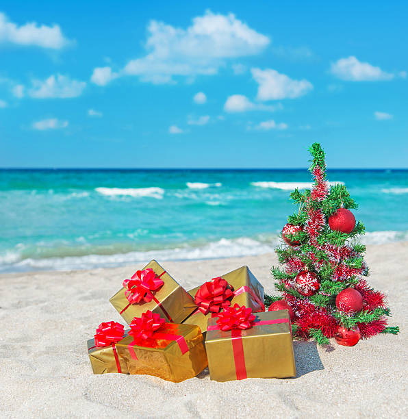 istock Christmas tree and many gift boxes on sea beach 459893419