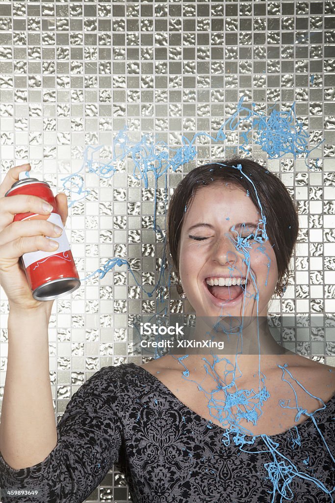 Young woman laughing and spraying party string over herself Party String Stock Photo