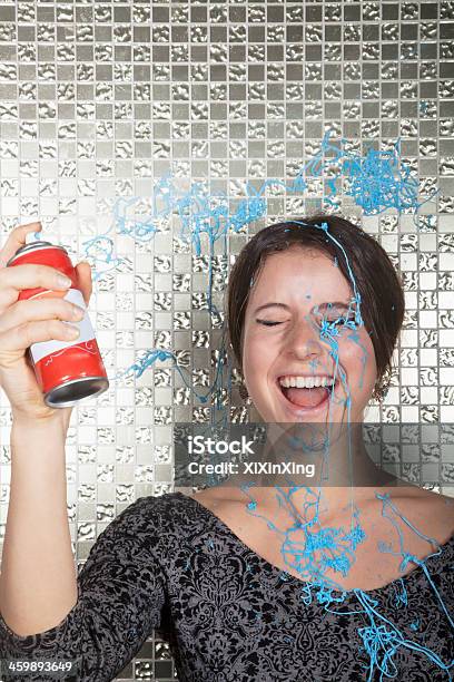 Young Woman Laughing And Spraying Party String Over Herself Stock Photo - Download Image Now