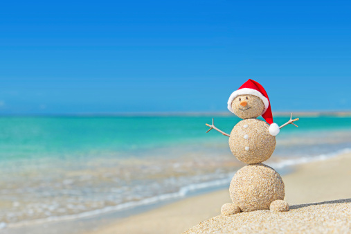 Smiley sandy snowman in red santa hat. Holiday concept for New Years and Christmas Cards.