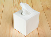 A photograph of a white tissue box on a hardwood floor