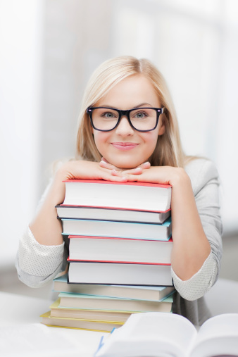 people, education and reading concept - smiling student woman in eyeglasses with stack of books