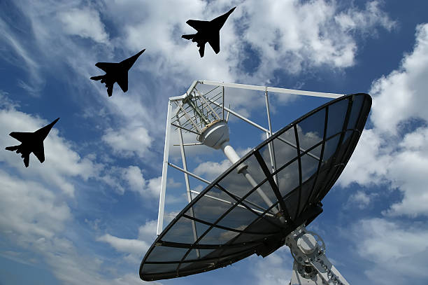 A large satellite radar flown over by three fighter jets