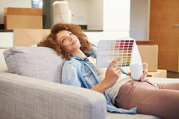 istock Woman Sitting On Sofa Looking At Paint Charts 459921951