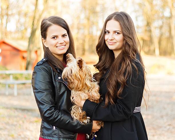 Beautiful brunette sisters holding their Yorskshire terrier.